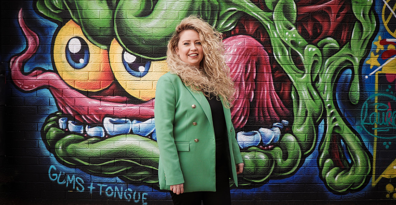 Photo of Aisling Doherty standing in front of a vibrant street art - Wibble Web Design & Development